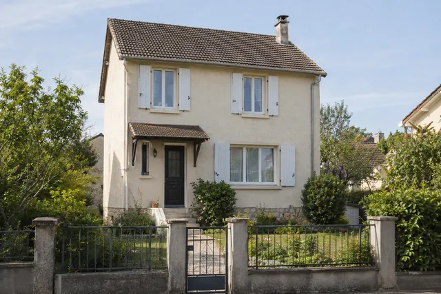 Maison familiale avec volets blancs et petit jardin de façade, illustration d’un projet de vente.